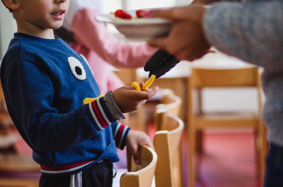 Kind erh&auml;lt Essen in der Tagesbetreuung